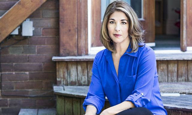 Naomi Klein sitting on the wooden steps of her Toronto home